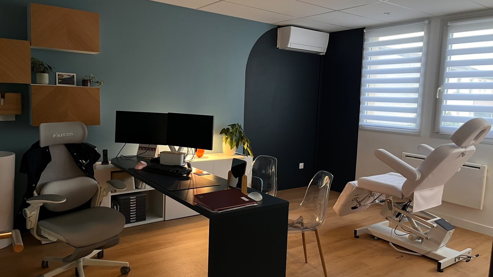 Une salle de consultation du cabinet : bureau, fauteuil d’examen et mur bleu